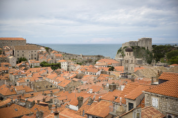 Fototapeta premium View over the orange rooftops of old town Dubrovnik from the ancient city wall with cloudy weather, Croatia
