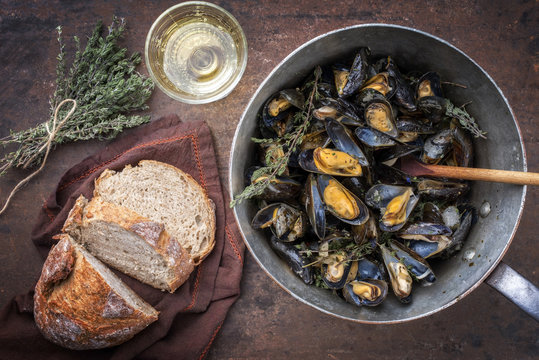 Traditional barbecue Italian blue mussel with farmhouse bread and white wine as top view in a casserole