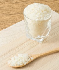 Uncooked Japanese Rice in Wooden Spoon and Glass Cup