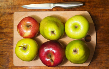 A top view of the six green and red apples on the cutting board