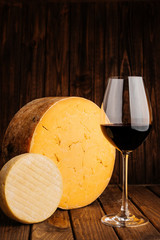 Authentic Crafted Cheese with Glass of Red Wine on Wooden Brown Background.
