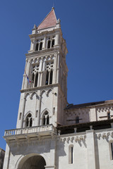 Fototapeta na wymiar Bell tower of the Cathedral of St. Lawrence with blue sky in the background, Trogir, Croatia, built in the Romanesque-Gothic style