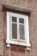 Fototapeta na wymiar Closed white wooden shutter of a old house