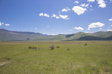 Countryside landscape at spring with field and mountain in the background and blue sky and fluffy white clouds, Croatia