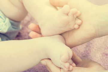 Baby feet in mother hands. Tiny newborn baby feet, concept of happy family. Fake color tone of photo..