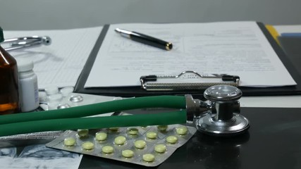 A doctor's table with pills and syrups in a modern hospital. Stethoscope with a dropper and syringes in the medical office. A nurse writes a prescription to a sick patient. The doctor checks new drugs - Powered by Adobe