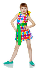 A little girl in a dress with a pattern from multi-colored circl