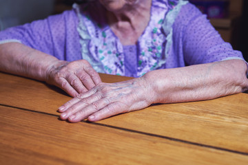 Obraz na płótnie Canvas old senior woman hands on wooden table