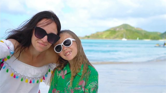 Beautiful mother and little daughter on Caribbean beach. Family taking selfie on tropical seashore. SLOW MOTION