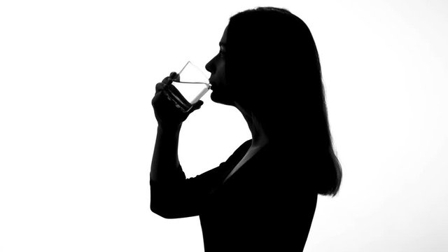 Female silhouette drinking glass of water, restoring ph balance, weight loss