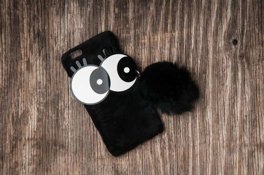 Black mobile phone case with pom pom pendant - Powered by Adobe