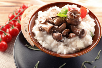 Bowl with risotto and mushrooms on table
