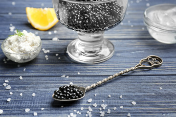 Spoon with delicious black caviar on table