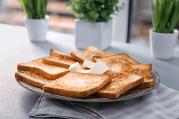 Plate with toasted bread and butter on table