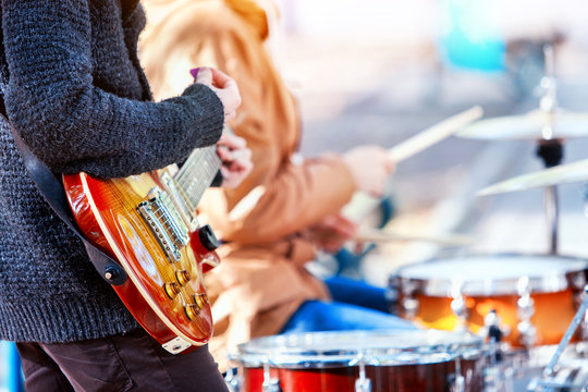 Festival music band. Hands playing on percussion instruments in city park. Drums with sticks closeup. Body part of male musicians. Sharpen is guitar and man hand. Hobby of adults.