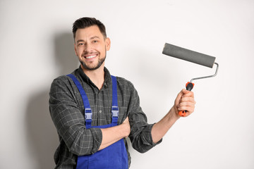 Fototapeta premium Young male decorator with paint roller on white background