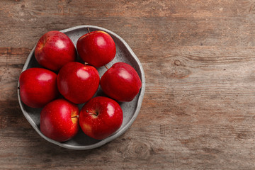 Plate with ripe red apples on wooden background