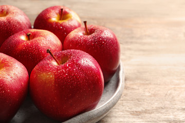 Plate with ripe red apples on wooden background