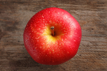 Ripe red apple on wooden background, top view