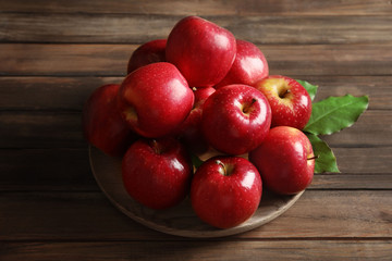 Plate with fresh ripe red apples on wooden background