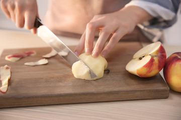 Woman cutting ripe apple at table