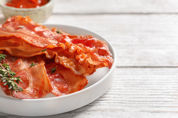 Plate with fried bacon on table