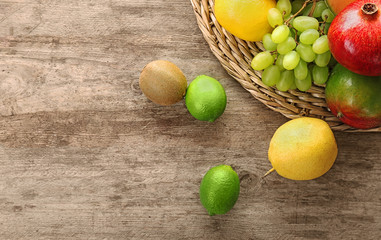 Wicker plate with fresh tropical fruits on wooden background