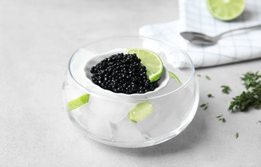 Fototapeta na wymiar Black caviar served with ice cubes and lime on light background