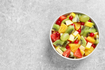 Bowl with fresh fruit salad on grey background