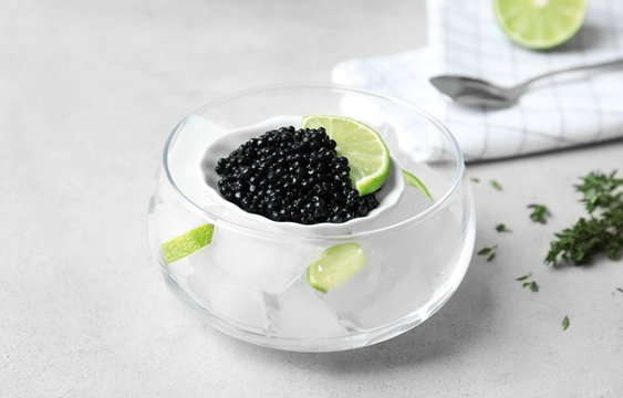 Black caviar served with ice cubes and lime on light background