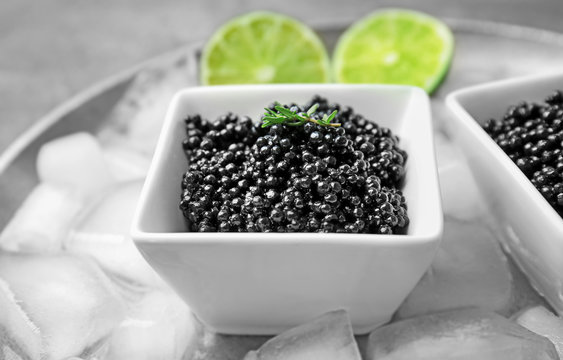 Black caviar served with ice cubes and lime, closeup
