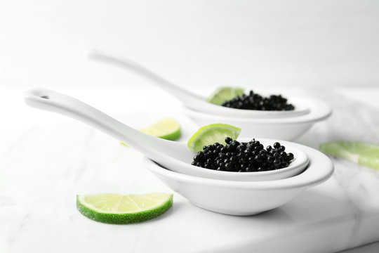 Ceramic spoons with black caviar and lime  on marble board