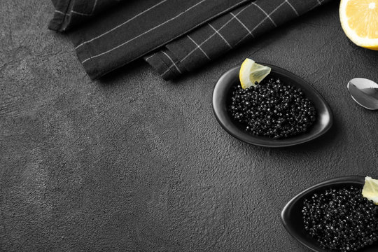 Bowls with black caviar on dark grey background