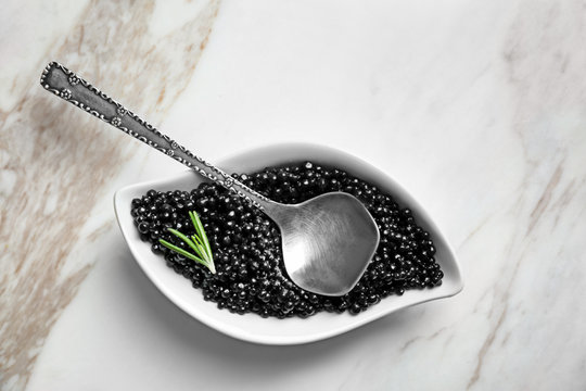 Ceramic bowl with black caviar on light background