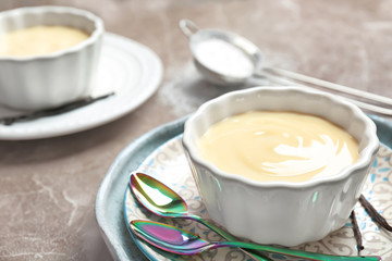 Bowl with vanilla pudding on light background