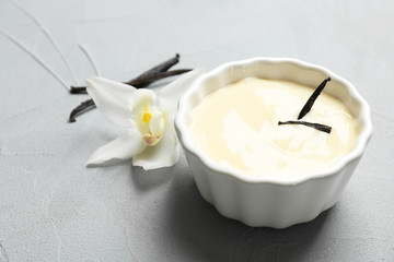 Vanilla pudding, sticks and flower on grey background