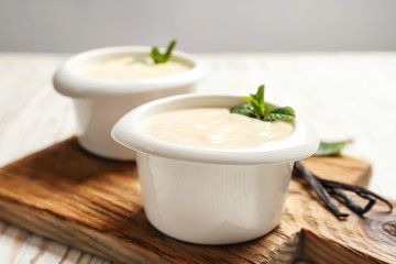 Vanilla pudding, sticks and fresh mint on wooden board
