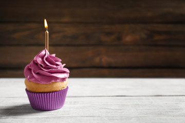 Delicious birthday cupcake with burning candle on table
