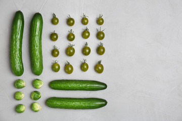 Different green vegetables on grey background, top view