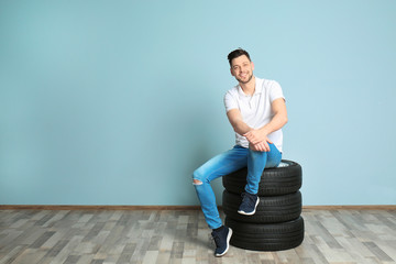 Young man with car tires on color wall background