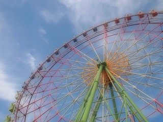 青空に立つ遊園地のカラフルな観覧車
