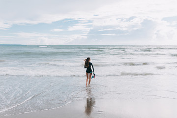 Surfer woman going surfing running with surfboard in the ocean. Female bikini girl walking with surfboard living healthy active lifestyle on tropic beach.