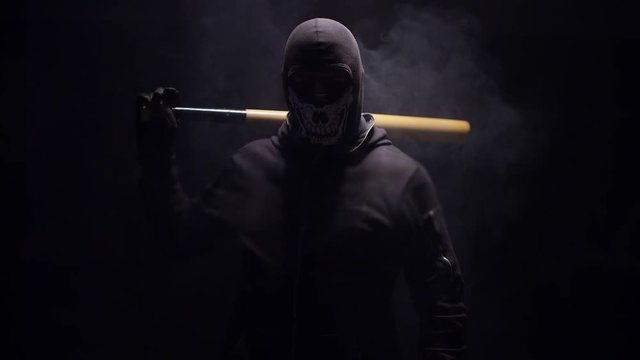 Portrait of masked hooligan with baseball bat on black background . Shot on RED cinema camera 