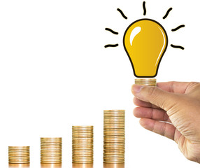 Man hand holding stack of money coins with light bulb ideas over money coin stack arranged as a graph on white background, concept of financial planning and save money
