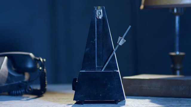 Vintage metronome beats rhythm on the dark room . Shot on RED Cinema Camera
