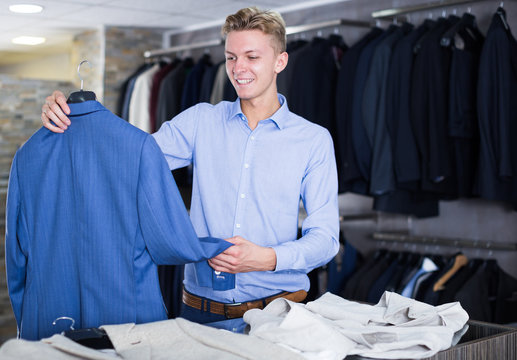 smiling man choosing jacket in the shop