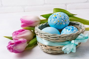 Happy Easter greeting with blue floral drcorated eggs in the wicker basket