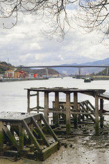 Nervion river and Rontegi bridge. The city of Bilbao, Spain, in the background. Old loading dock in the foreground.