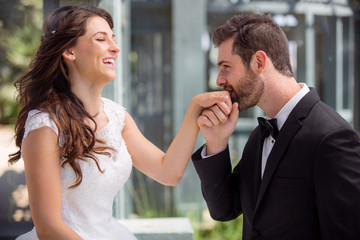 Groom and bride smile and share romantic moment kissing hand