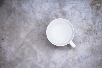 White cup with water on a light gray concrete background. Minimalism concept. Layout, copyspace for text